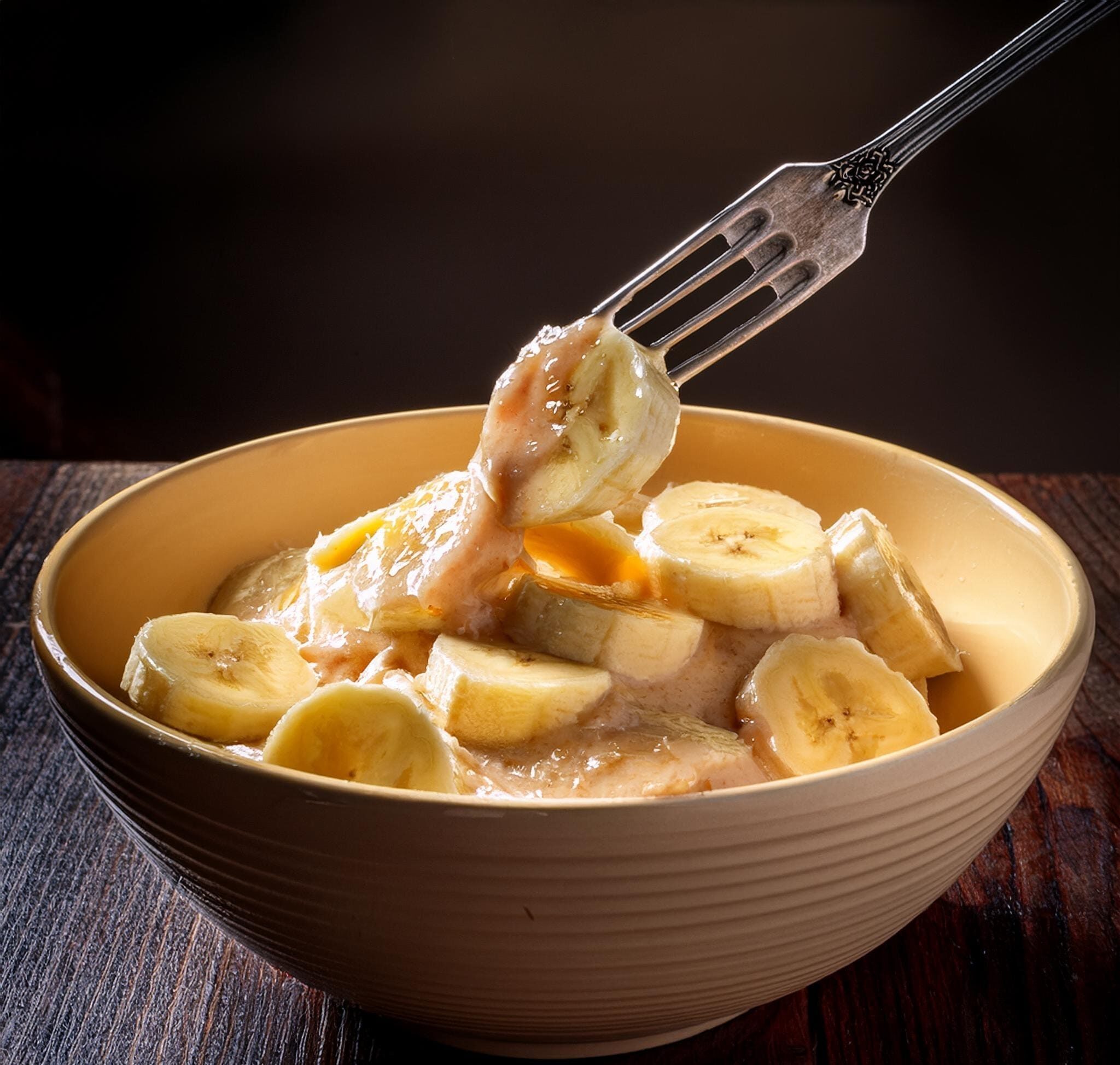 Classic Banana Bread Recipe A photo of a fork mashing ripe bananas in a bowl, ready to be folded into the wet ingredients